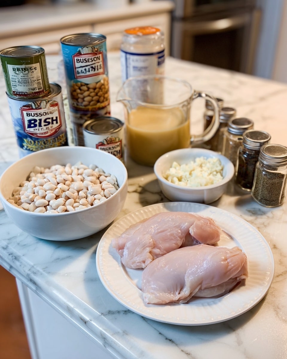 The image shows a white plate with two raw chicken pieces placed on the right side. To the left of the chicken plate, a large white bowl filled with chopped onions sits on a white marbled countertop. Behind the bowl, two cans of Bush's Best white beans stand stacked, and next to them is a can of green chili. A glass measuring cup holds creamy yellow liquid positioned centrally in the background. In front of this, a small white bowl contains minced garlic. Several spice containers with lids are arranged on the far right side of the counter. The white marbled surface and soft kitchen lighting complete the setting. Photo taken with an iphone --ar 4:5 --v 7