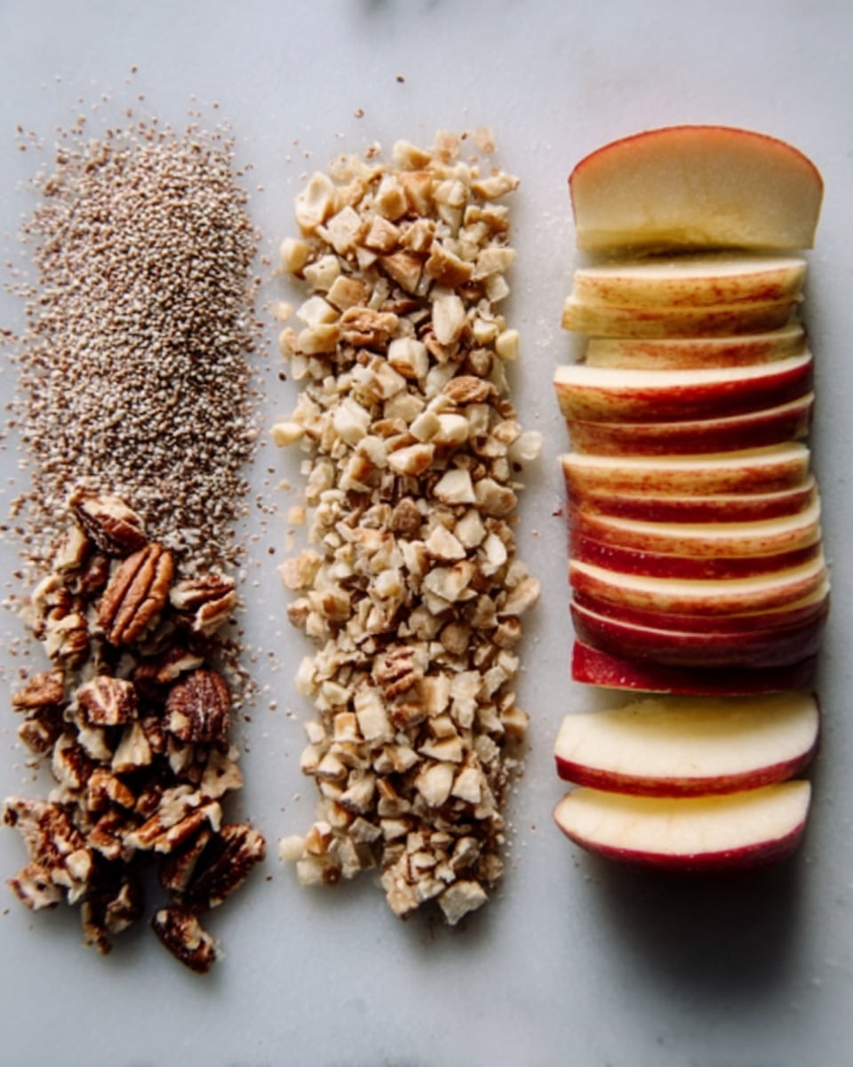 The image shows four neat rows on a white marbled surface. On the far right is a stack of sliced apple, thinly sliced with a red and yellow skin, each slice slightly lifted to show layers. Next to it on the left is a line of light brown flax seeds with a rough texture. To the left of the flax seeds is a line of chopped light beige cashews. On the far left is a row of mixed nuts, including small pieces of pecans with a brown and beige color showing rough textures. The lighting is soft and natural. photo taken with an iphone --ar 4:5 --v 7