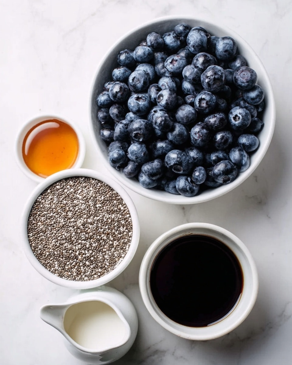 The image shows a white bowl full of fresh, dark blue blueberries. Below it, there is a white bowl filled with small, grey and white chia seeds with a rough texture. Next to the chia seeds is a small white cup with amber-colored honey, and in the middle left is a tiny white pitcher filled with white milk or cream. At the bottom of the image, there is a small white bowl with a thick, black liquid, likely vanilla extract. All these items are placed on a white marbled surface. photo taken with an iphone --ar 4:5 --v 7