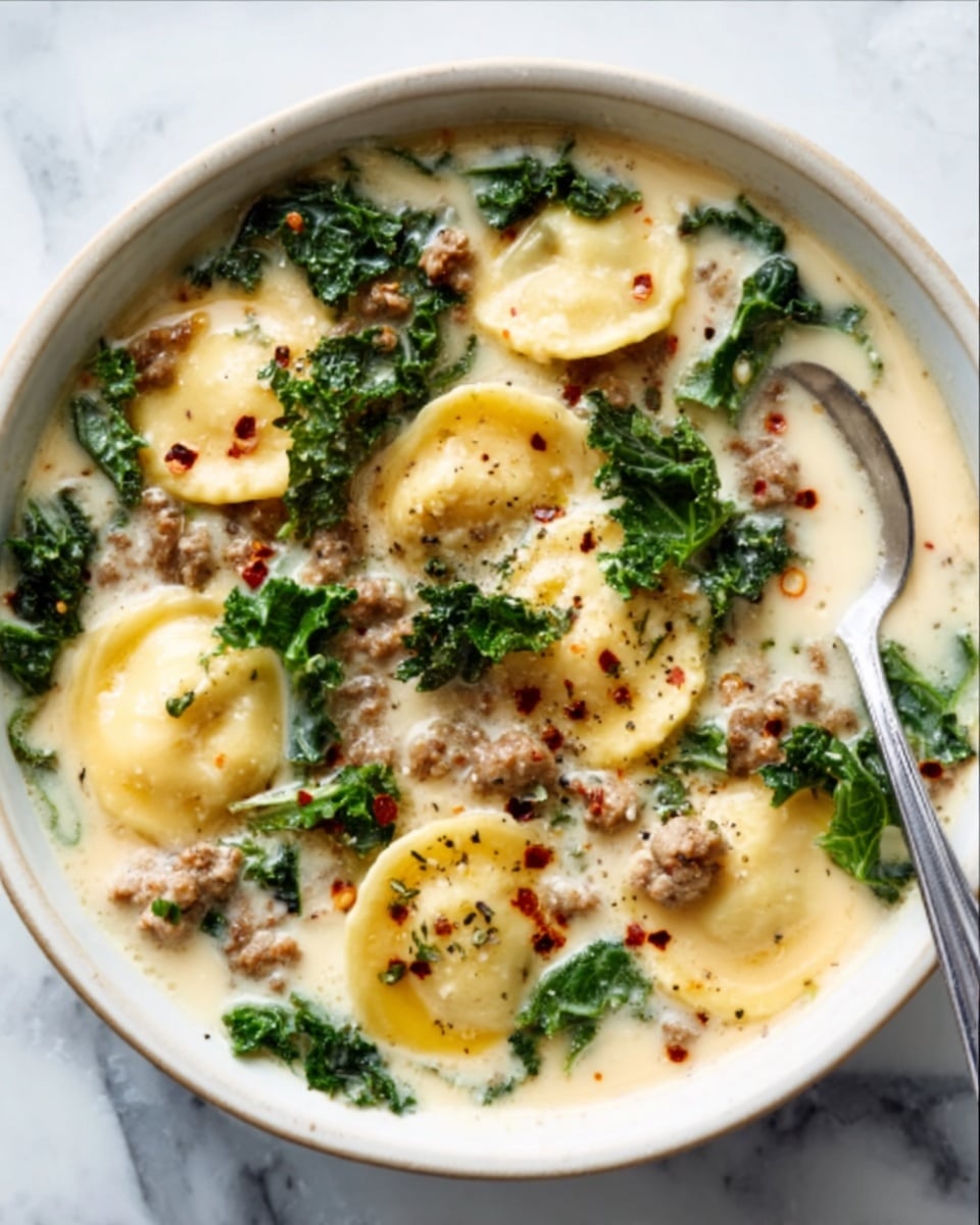 A white bowl filled with a rich, reddish broth, layered with plump yellow tortellini showing soft folds. Dark green leafy vegetables float on top, mixed with small pieces of brown meat and bits of ground meat dispersed throughout the soup. A silver spoon rests inside the bowl, partially submerged. The background is a white marbled texture with small white dishes nearby, one holding red chili flakes. Photo taken with an iphone --ar 4:5 --v 7