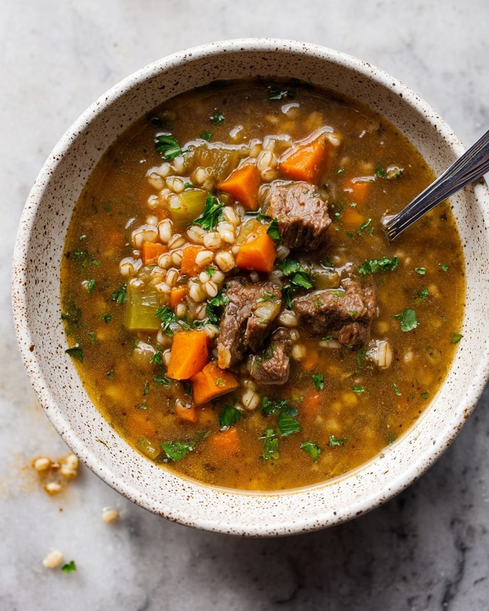 A white speckled bowl filled with a thick soup shows three main layers: a base layer of clear brown broth, a middle layer of tender brown meat chunks, and a top layer of diced orange carrots, small green celery pieces, light brown grains, and chopped fresh parsley scattered on top. A silver spoon is partially submerged on the right side, resting inside the bowl. The bowl sits on a white marbled surface with a few small crumbs around it. photo taken with an iphone --ar 4:5 --v 7