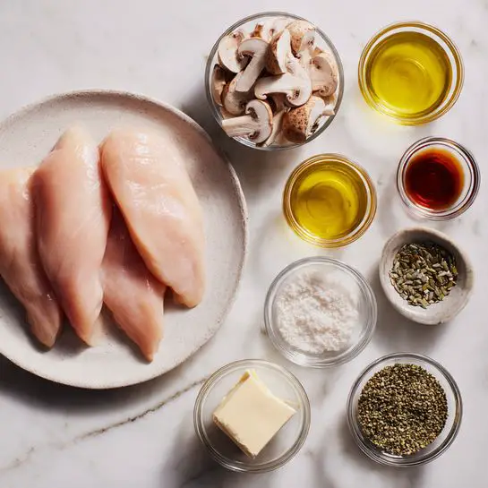 A white round plate on the left holds three raw chicken fillets with a light pink color and smooth texture. To the right, there are eight small glass bowls arranged in three rows on a white marbled surface. The top row has sliced light brown mushrooms in the left bowl and a bowl with pale yellow oil on the right. The middle row has a reddish brown liquid in the left bowl and a dark brown liquid in the right bowl. The bottom row from left to right contains a small bowl with a block of butter, a bowl of white powder, a bowl with light green seeds, and a bowl with darker green seeds. Photo taken with an iphone --ar 4:5 --v 7