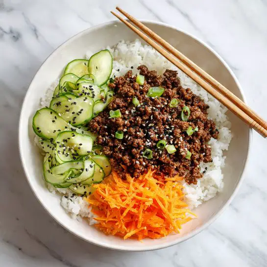 A white bowl holds a dish with three main layers around in sections. The bottom layer is white cooked rice filling the base. On top of the rice is a serving of cooked ground beef seasoned and topped with black and white sesame seeds, showing a rough, crumbly texture on one side. Next to the beef, there are thinly curled fresh cucumber slices with a light green color and visible seeds. Adjacent to the cucumbers is a small pile of bright orange shredded carrot with a soft and shredded texture. A pair of light wooden chopsticks rests on the edge of the bowl. The bowl is set on a white marbled surface. photo taken with an iphone --ar 4:5 --v 7