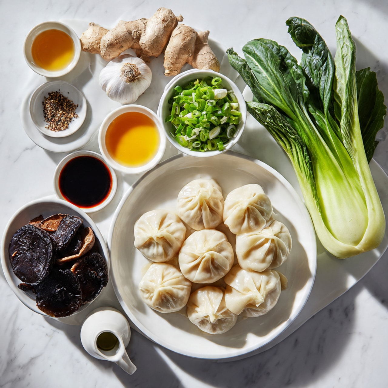 A white plate holds a pile of light beige dumplings with slight wrinkles, placed slightly to the right center. Above the dumplings, there is a small white bowl filled with bright green chopped spring onions. To the right side, two fresh bok choy heads show green leaves with moisture droplets and pale green stems. Below the dumplings, a white bowl contains dark brown dried shiitake mushrooms with a smooth texture and some curved caps. Above the plate to the left, another white plate holds three garlic cloves, a ginger root with a light brown surface, and three small bowls containing dark soy sauce, light yellow oil with black pepper, and a red-brown sauce. Near the lower left corner, a small white jug contains an orange-colored sauce. The whole scene is set on a white marbled surface, with bright light highlighting the fresh and natural colors of each item. Photo taken with an iphone --ar 4:5 --v 7