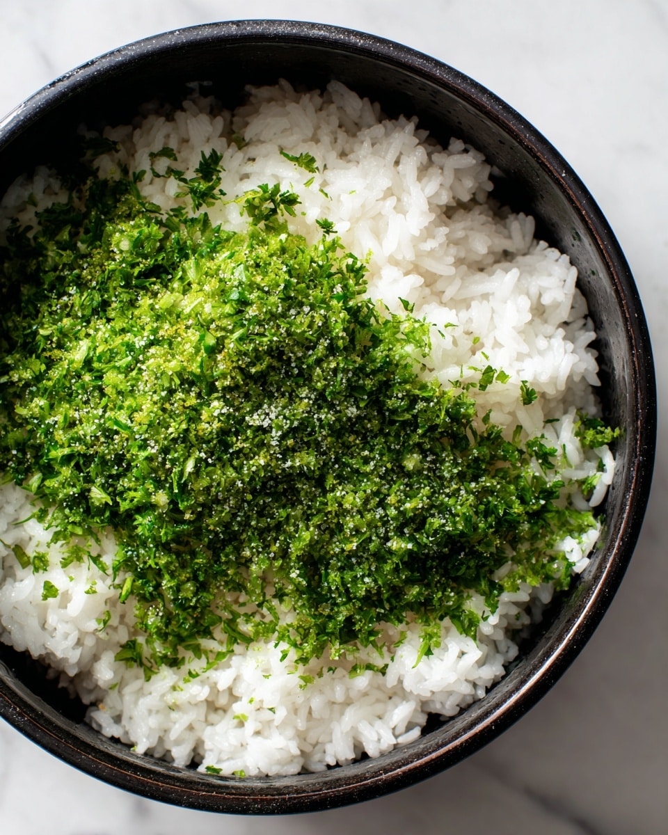 A close-up of a black pot filled with white cooked rice forming the bottom layer, topped with a generous pile of finely chopped fresh green herbs sprinkled with coarse salt. The rice has a soft, fluffy texture with visible grain separation, while the herbs add a vivid green color and a fresh texture contrast. The black pot edges frame the contents tightly, set against a white marbled background. photo taken with an iphone --ar 4:5 --v 7