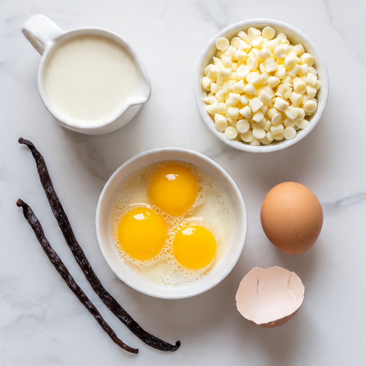 The image shows a white bowl in the center with three raw egg yolks and egg whites inside, with a few bubbles on the surface. To the bottom right are three broken brown eggshells placed in a row. On the top right, there is a white bowl filled with small white chocolate chips. At the top left, two dark, wrinkled vanilla pods lie side by side on the white marbled surface. At the bottom left, there is a small white pitcher filled with a pale cream liquid. The whole setup is on a white marbled texture. photo taken with an iphone --ar 4:5 --v 7