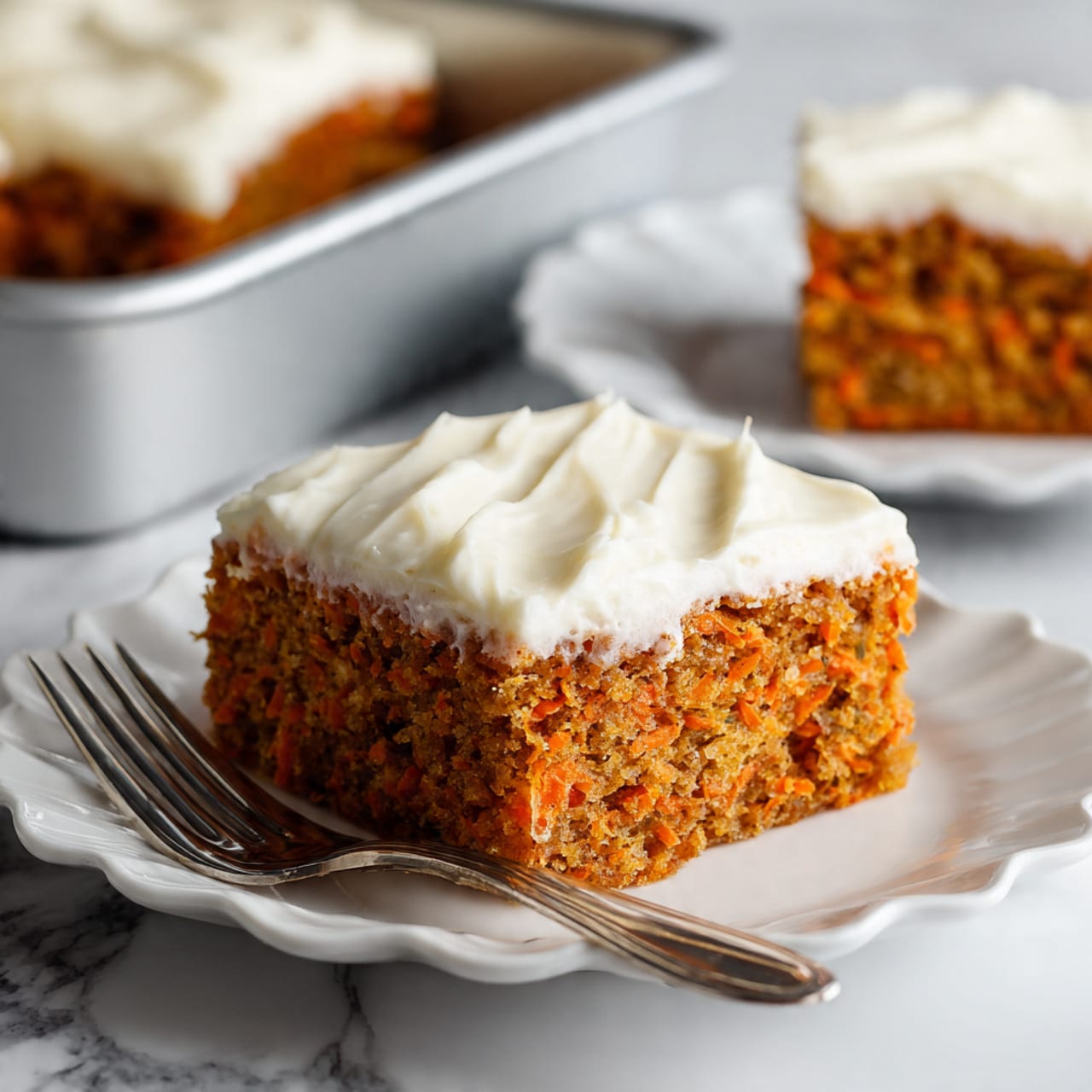 A square piece of carrot cake with one thick layer of light orange-brown cake filled with small bits of carrot, topped with a thick, smooth layer of creamy white frosting. It sits on a white plate with soft curves and a slight shine. A small silver fork rests on the plate to the right of the cake. In the blurred background, there is another piece of cake on a similar plate and part of a baking tray. The whole scene is set on a white marbled surface. photo taken with an iphone --ar 4:5 --v 7