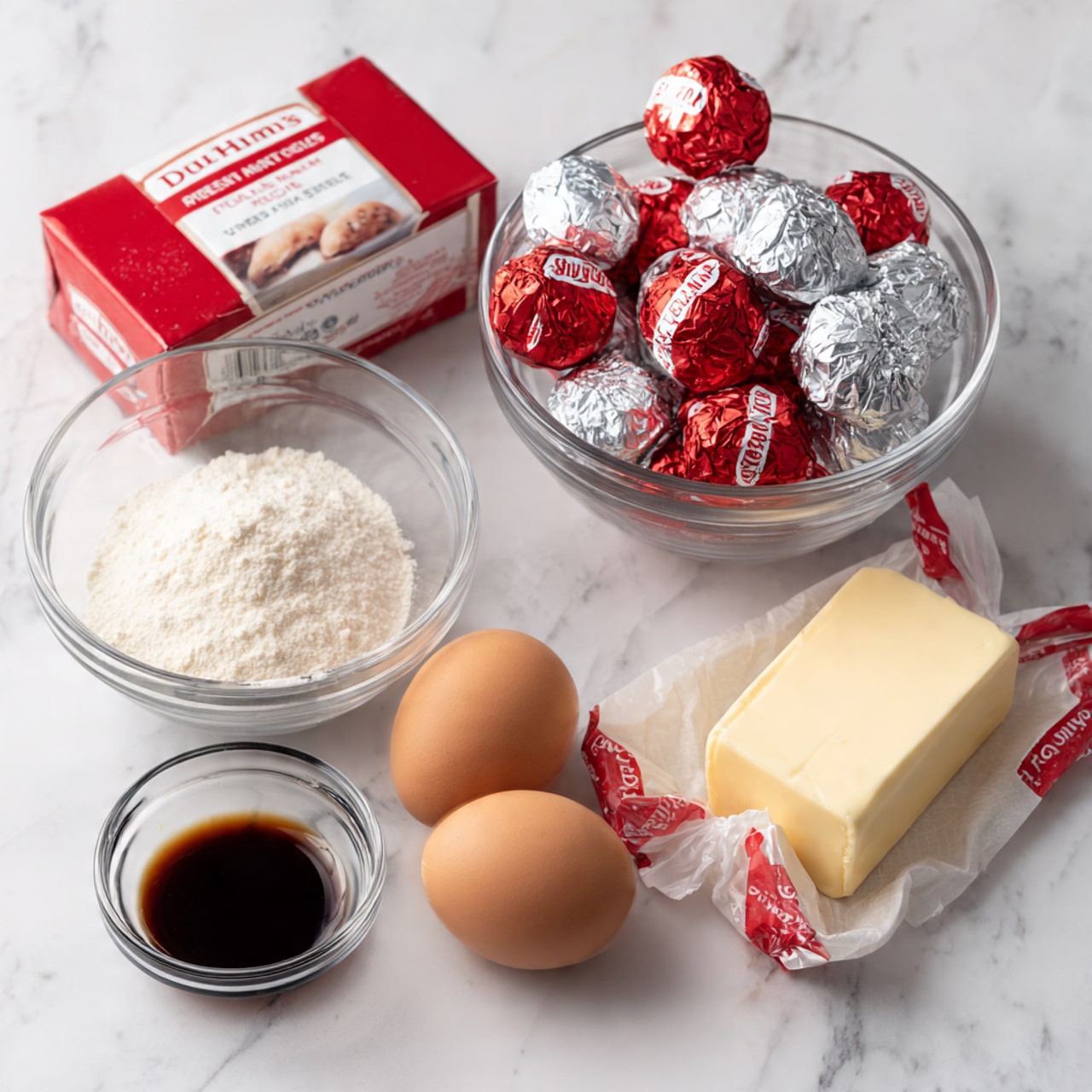 The image shows ingredients for a cake arranged on a white marbled surface: a red velvet cake mix box with a picture of the cake on it, two brown eggs, a stick of butter wrapped in paper, a small glass bowl with clear vanilla extract, a small white bowl filled with sugar, and a clear bowl containing foil-wrapped red, silver, and blue candy small balls. All items are spaced out neatly in an organized layout. Photo taken with an iphone --ar 4:5 --v 7