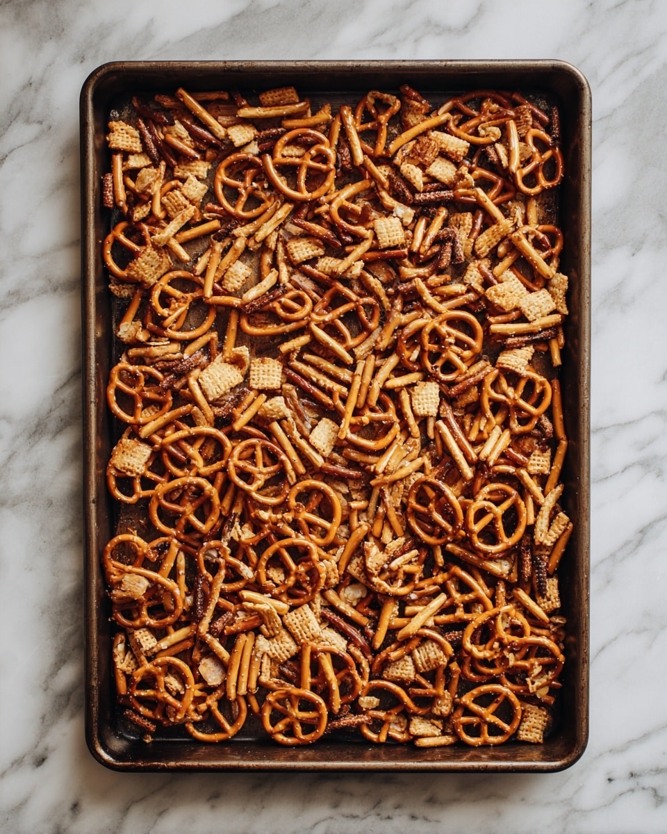 The image shows a baking tray filled with many small twisted pretzels and irregular crispy snacks, scattered all over the tray in a single layer. The pretzels are shiny and brownish, while the other snacks are light brown and crunchy, creating a textured mix. The tray sits on a white marbled surface, and the overall look is rustic and inviting. photo taken with an iphone --ar 4:5 --v 7