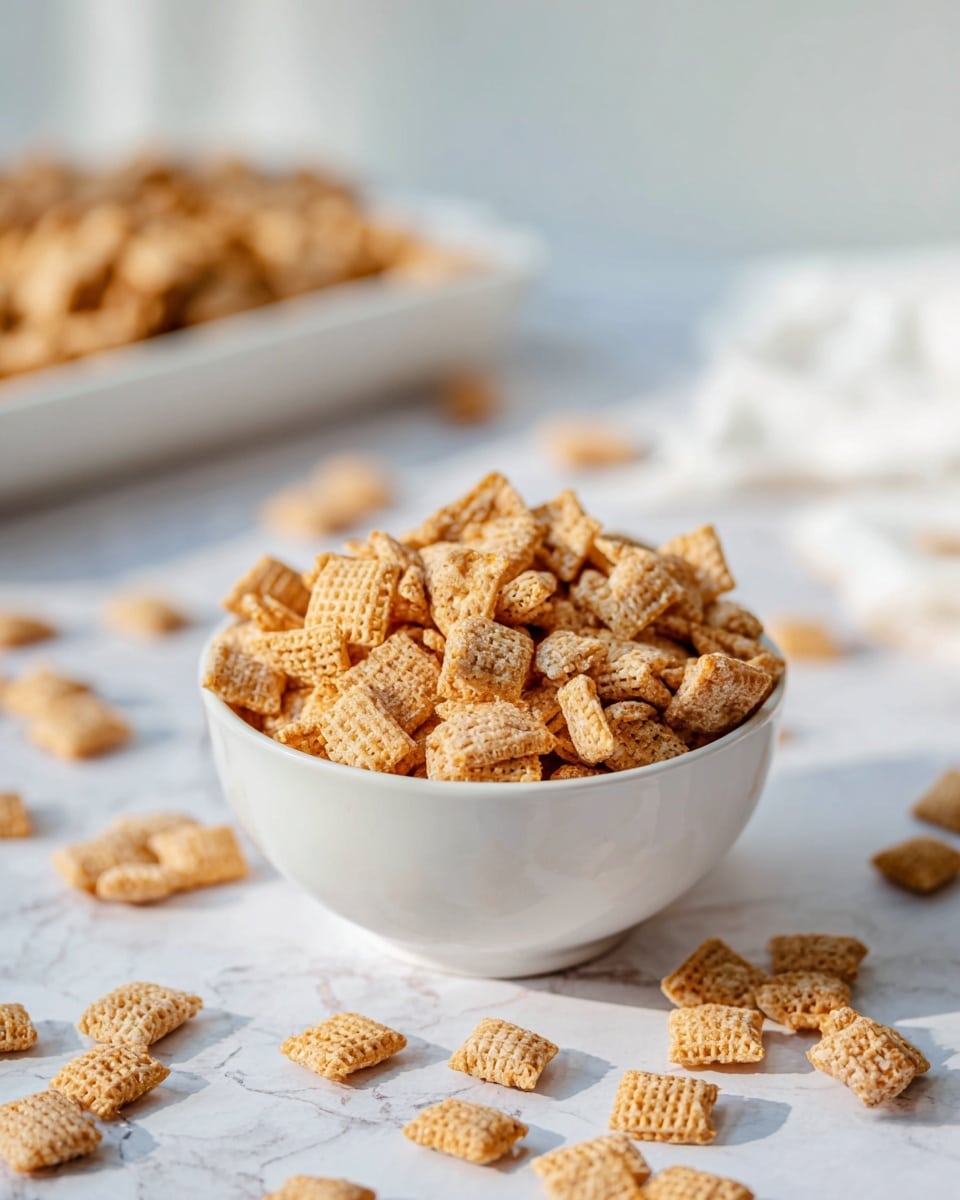 A white bowl filled with square-shaped golden cereal pieces sits in the center, with some cereal pieces scattered around the bowl on a white marbled surface. Behind the bowl, there is a white tray full of the same cereal, slightly out of focus. The cereal pieces have a crispy texture and are light brown in color. The overall setting is bright and clean, with soft natural lighting highlighting the cereal’s details. Photo taken with an iphone --ar 4:5 --v 7