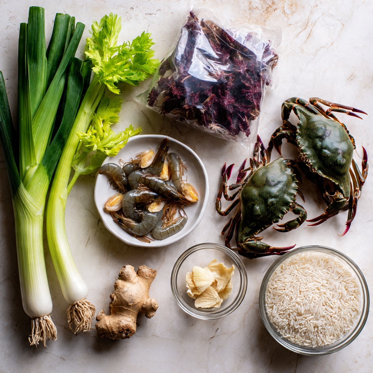 The image shows fresh cooking ingredients arranged on a white marbled texture surface. On the left, there are two green onions and a stalk of celery with bright green leaves. Next to them is a clear plastic bag filled with raw dark-colored shrimp. Above the shrimp bag, there is a white bowl holding two live dark green crabs with purple bands on their legs. To the right of the crabs, a clear glass bowl contains small beige dried scallops and a piece of fresh ginger root. Below the glass bowl, there is a small round clear container filled with white rice grains. photo taken with an iphone --ar 4:5 --v 7