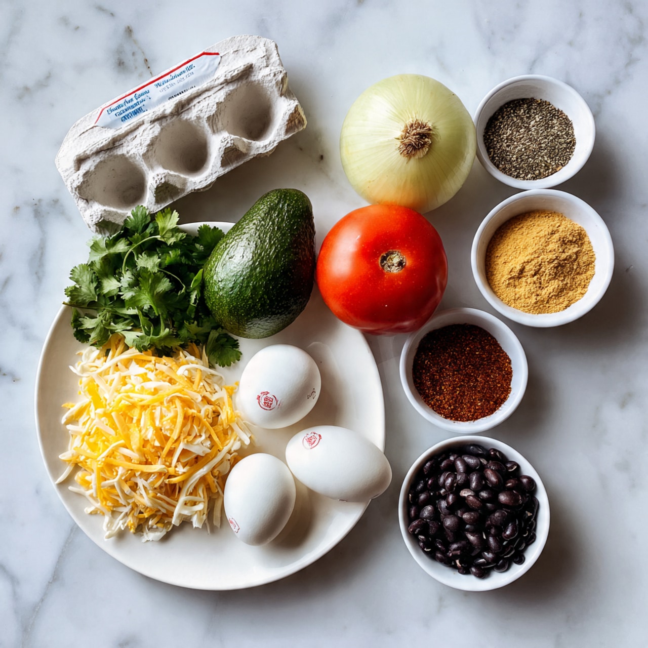 A white round plate holds five ingredients: a bunch of green cilantro on the left, a red tomato next to it, a dark green avocado below the tomato, a whole yellow onion on the right, and two white eggs in the front with red stamps. To the right of the plate are three small white bowls placed vertically: the top bowl is filled with shredded yellow and white cheese, the middle bowl contains two kinds of powder spices, half golden brown and half dark red, and the bottom bowl is filled with small black beans. Above the plate is a white egg carton with red and blue text. All items are set on a white marbled surface. Photo taken with an iphone --ar 4:5 --v 7