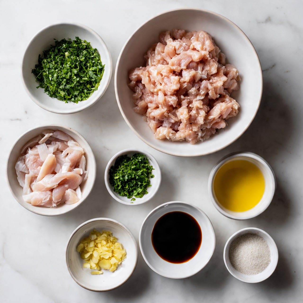 The image shows several white bowls arranged on a white marbled surface. One large white bowl contains minced raw chicken with a pinkish color and soft texture. Below it, another white bowl holds thin raw chicken strips that are light pink. Around these bowls are smaller white bowls containing ingredients: finely chopped green herbs, a dark brown liquid sauce, bright yellow chopped ginger, and a mix of finely minced white garlic with a woman’s hand small amount of ginger on the side. There is also a small white bowl with a white powdery ingredient. All items are neatly placed and clearly visible. Photo taken with an iphone --ar 4:5 --v 7