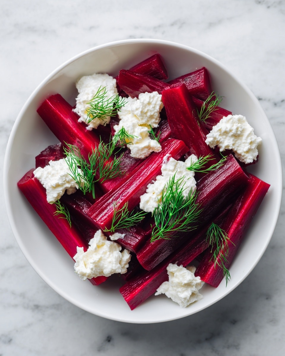 The image shows a close-up of a white bowl filled with a salad made of dark red beetroot sticks arranged in the center. On top of the beetroot are small, soft white dollops of cheese, and some bright green dill leaves are scattered around and on the beetroot for decoration. The background is a white marbled texture, giving a clean and fresh look. Photo taken with an iphone --ar 4:5 --v 7