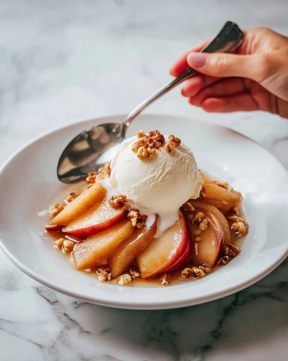 A white plate holds a dessert with several thick, warm golden-brown apple slices arranged in layers, covered with a scoop of smooth white ice cream that is slightly melting over the fruit. Around the apple slices and ice cream are small pieces of light brown nuts, adding texture. A silver spoon rests on the side of the plate, with a woman's hand holding it slightly above the dish. The background is a white marbled surface. Photo taken with an iphone --ar 4:5 --v 7