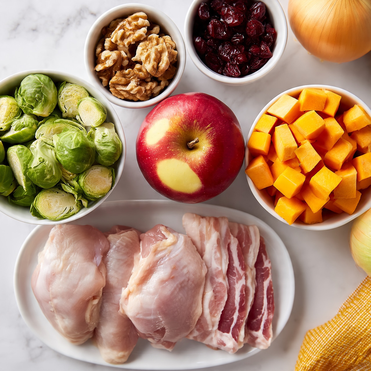 square image The image shows a collection of fresh ingredients arranged neatly on a white marbled surface. There is a white plate holding three raw chicken thighs and two raw strips of bacon side by side in the bottom left corner. To the left, a white bowl is filled with halved Brussels sprouts, showing their green leafy texture. In the middle, a whole red apple with light yellow patches sits on the surface. Above the apple, a small white bowl contains a handful of walnut halves, displaying their rough brown texture. To the right of the apple, there is a white bowl filled with bright orange cubed sweet potatoes. Above that, another small white bowl holds a serving of dark red dried cranberries. On the bottom right edge, part of a whole yellow onion and a yellow checkered cloth are visible. The lighting is bright, and the photo was taken with an iphone --ar 4:5 --v 7