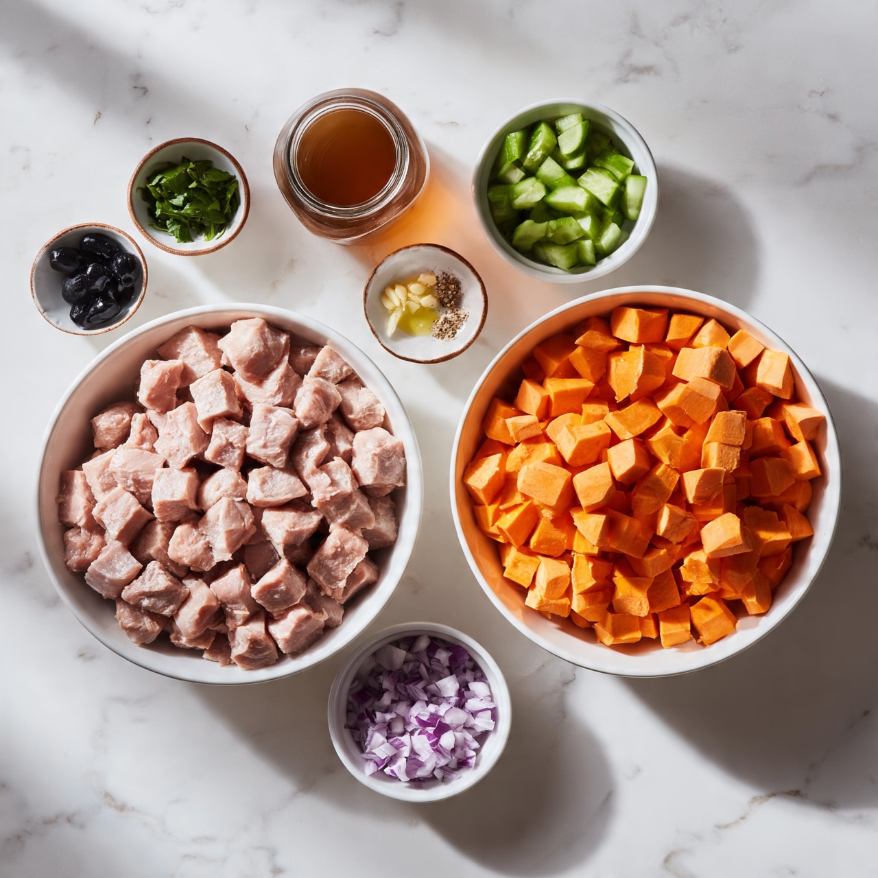 square image The image shows several white bowls and small glass containers of ingredients arranged on a white marbled surface. One large white bowl holds cubed light pink raw meat. Another large white bowl contains bright orange cubed sweet potatoes. A smaller white bowl is filled with green cucumber pieces, and another small white bowl has chopped red onions. There is a glass jar with brown liquid, a small bowl with chopped green leaves, and small dishes with minced garlic, black olives, a small amount of oil, and some spices. A woman's hand is not visible in this scene. photo taken with an iphone --ar 4:5 --v 7